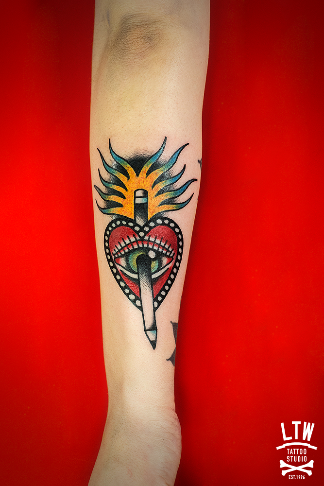 Corazón y lápiz tatuados por Dennis