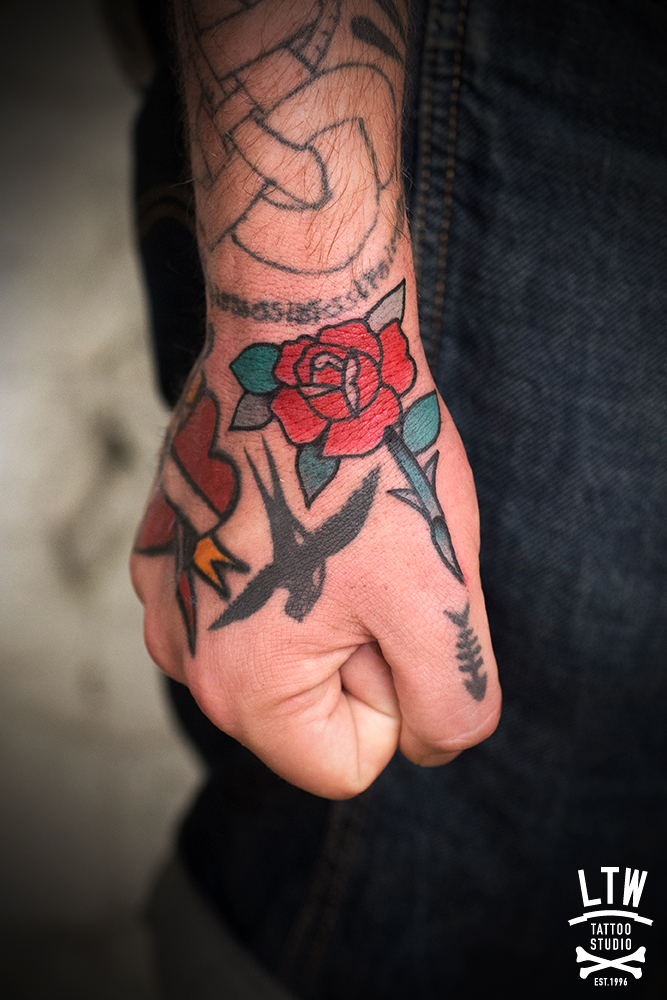 Tatuatge d'una rosa en estil tradicional a la ma pel Dennis