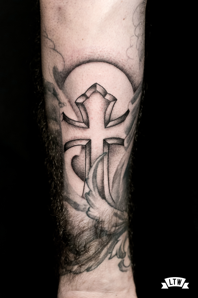 Cross tattooed in black and grey by Alexis